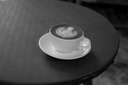 Cup of coffee with a latte art design on a saucer on a dark wooden table.