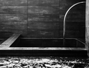 Black and white tiled outdoor shower with water flowing.
