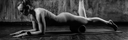 Person lying on a yoga mat with a foam roller in a black and white photo