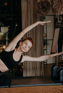 Woman practicing pilates in a studio with equipment and decor.