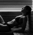 Person sitting in a sauna with wooden walls